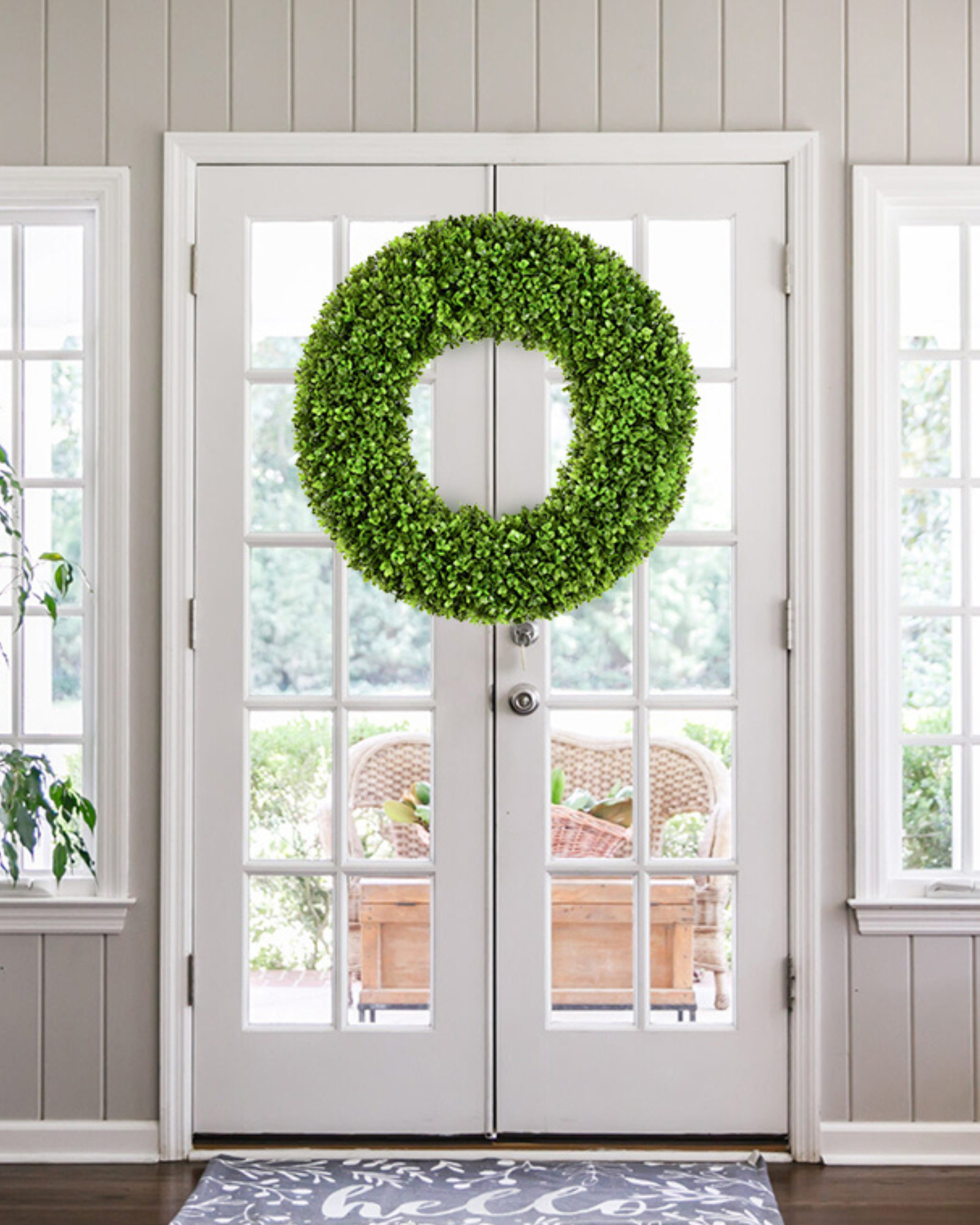 20 inch year round artificial boxwood wreath is hanging on the front door.