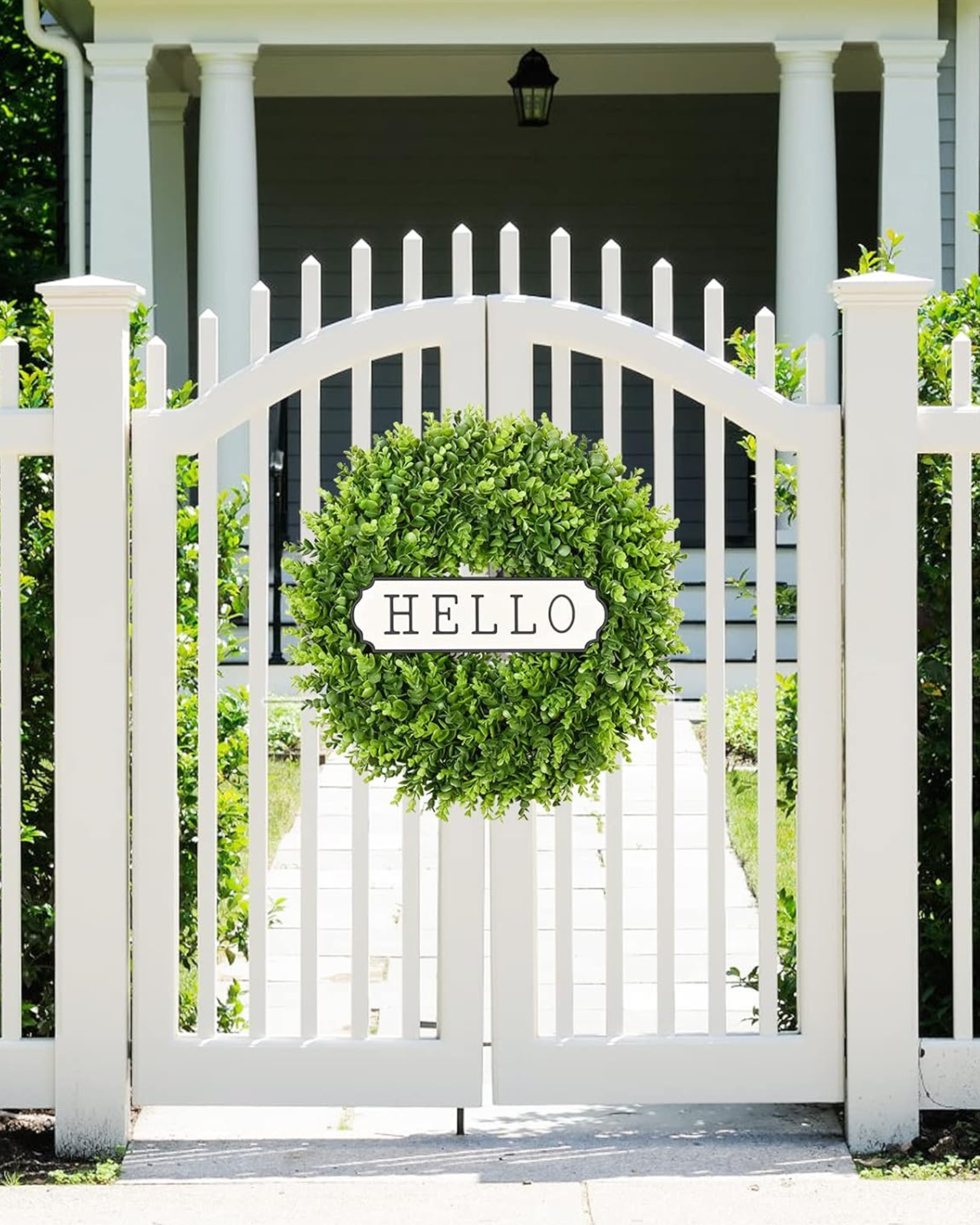 A 20 inch year round greenery boxwood wreath is hanging on the fence.