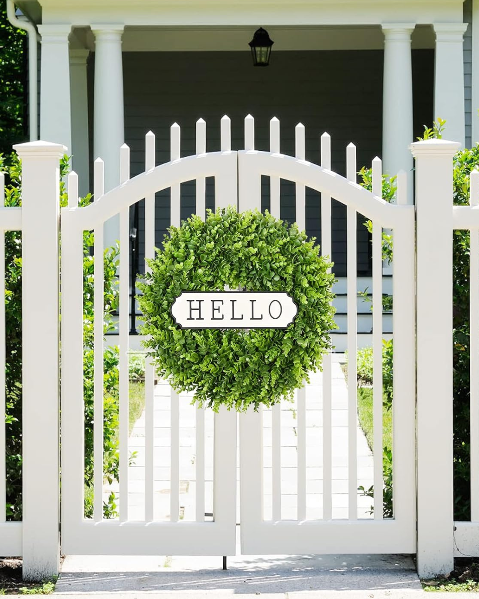 A 24 inch year round greenery boxwood wreath is hanging on the fence.