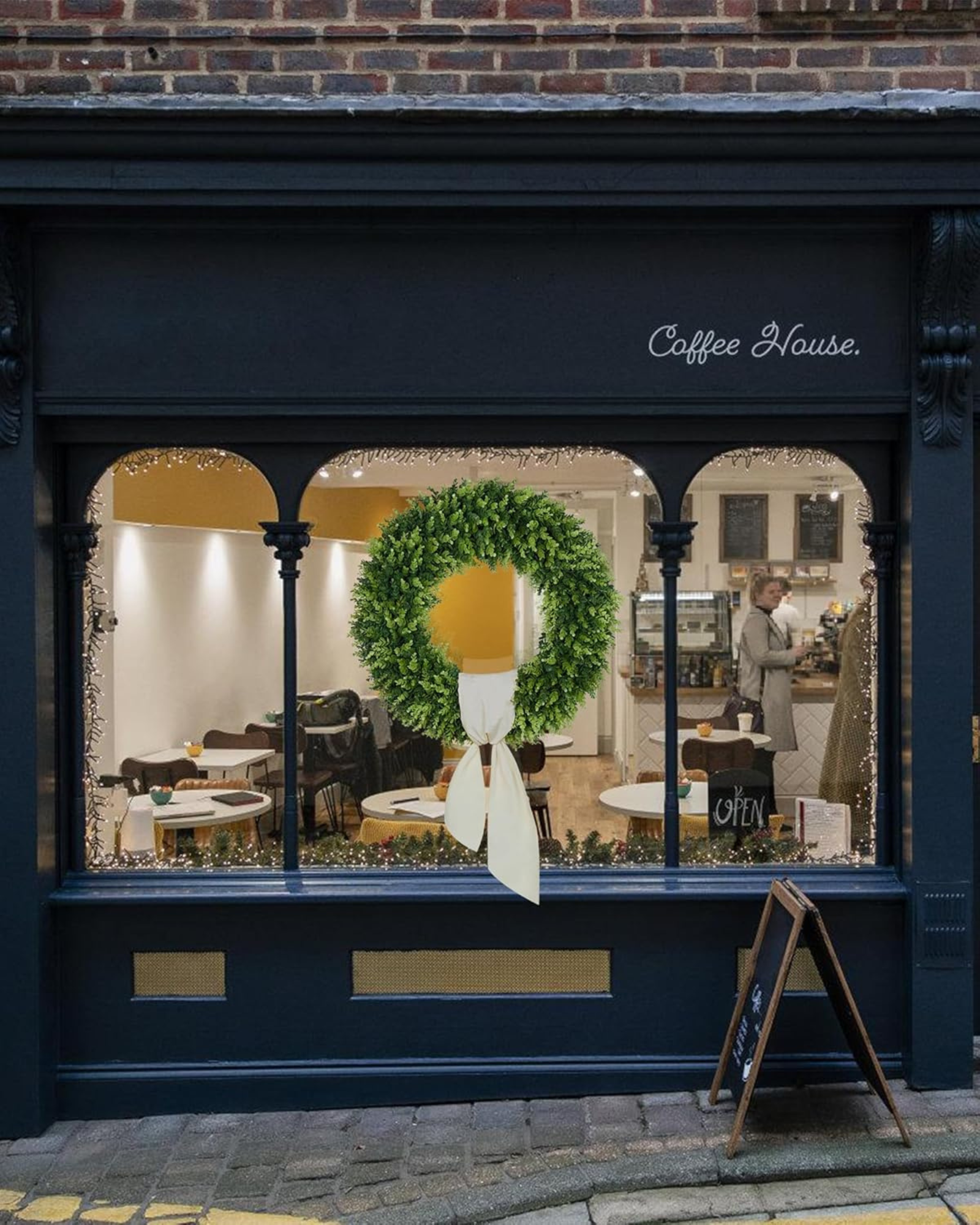 A 32 inch year round large boxwood wreath is hanging on the window.