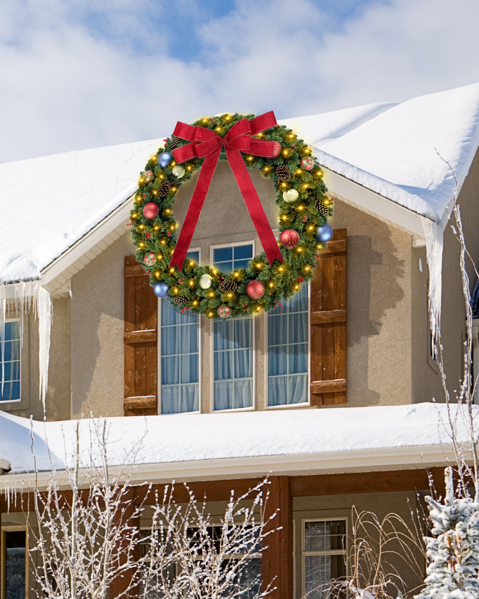 A 60 inch prelit large christmas wreath is hanging on the front door.