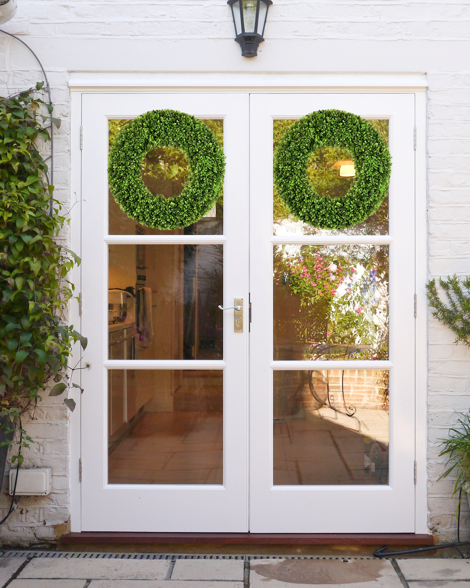 Two 20 inch year round artificial boxwood wreaths is hanging on the front door.